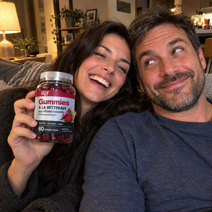 Un couple rit sur le canapé, elle tient le pot de gummies à la betterave