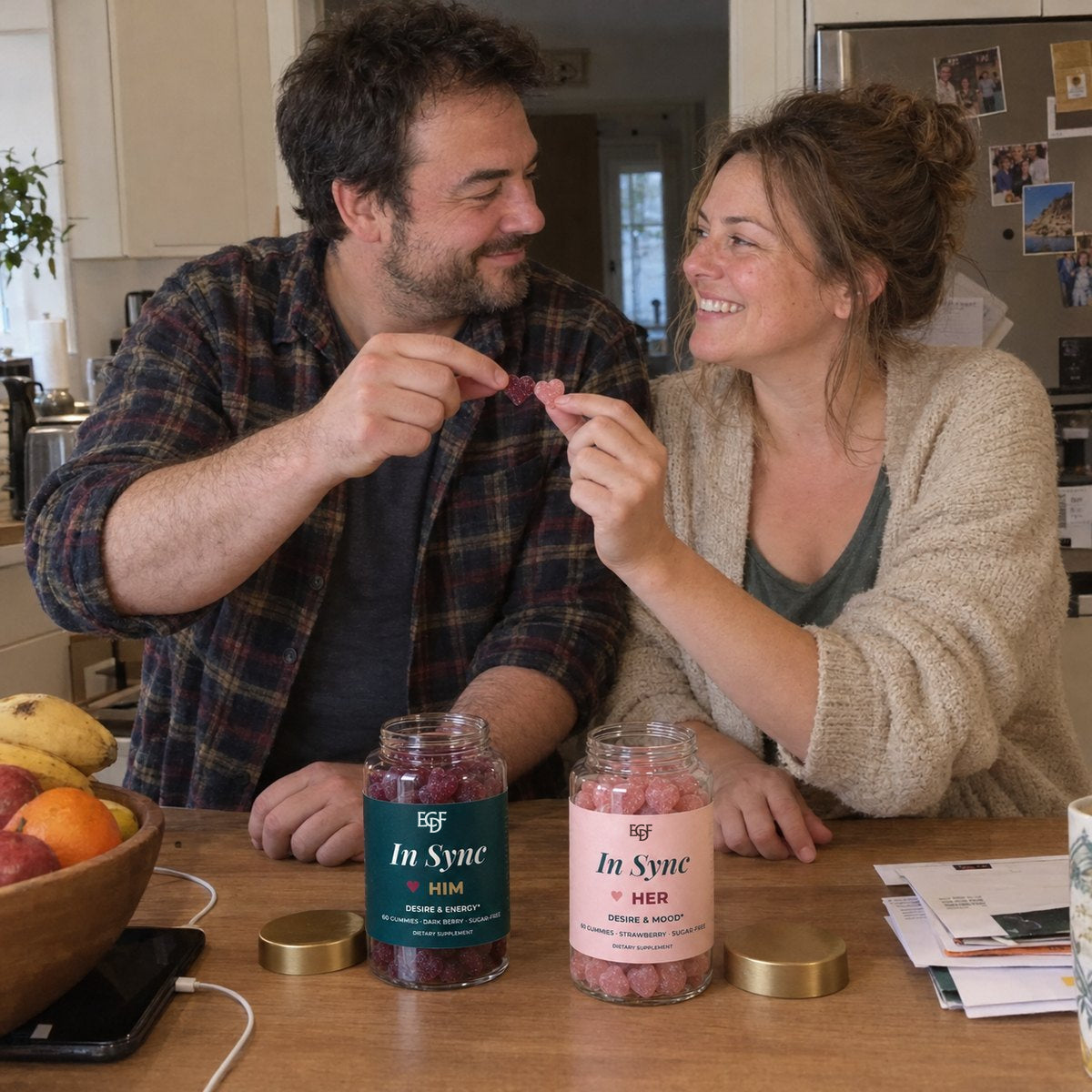 Un couple à la table de la cuisine trinque en riant avec ses gummies, les pots LUI et ELLE devant eux